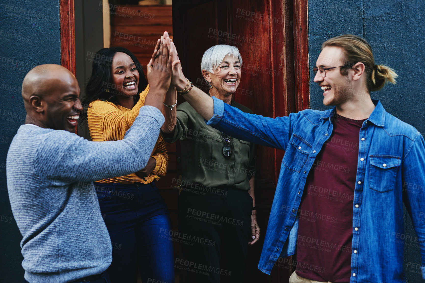 Buy stock photo Shot of a group of businesspeople joining together for a high five while standing outside their office building