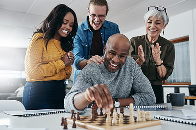 Buy stock photo Shot of a mature businessman playing chess in his office with his colleagues rooting and watching in the background