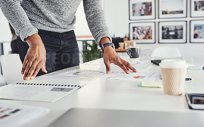 Buy stock photo Cropped shot of an unrecognizable businessman looking over paperwork while standing in his office