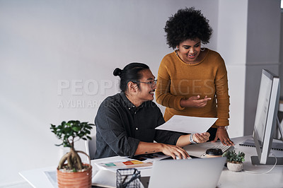 Buy stock photo Cropped shot of two young businesspeople working together with a computer and paperwork in the office