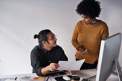 Buy stock photo Cropped shot of two young businesspeople working together with a computer and paperwork in the office