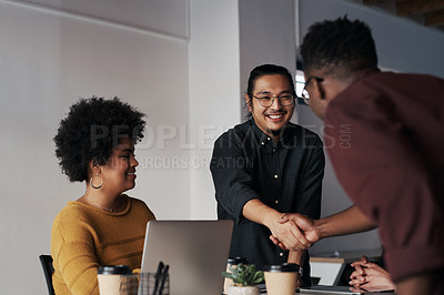 Buy stock photo Cropped shot of a group of young businesspeople greeting each other with a handshake before sitting down in the office