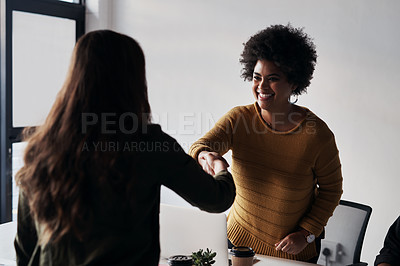 Buy stock photo Cropped shot of two young businesswomen greeting each other with a handshake before sitting down in the office