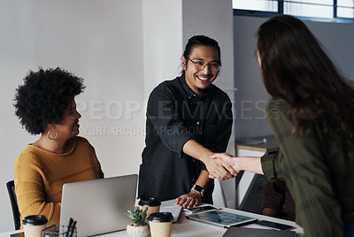 Buy stock photo Cropped shot of a group of young businesspeople greeting each other with a handshake before sitting down in the office