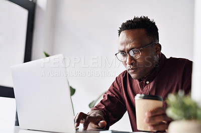 Buy stock photo Cropped shot of a handsome young businessman sitting alone and working on his laptop in the office
