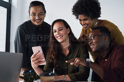 Buy stock photo Cropped shot of a diverse group of businesspeople looking at a cellphone together in a modern office