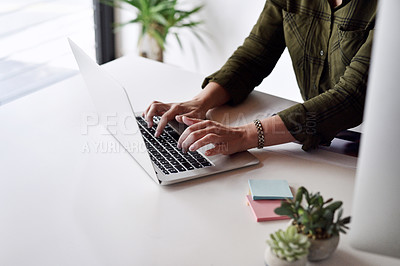Buy stock photo Cropped shot of an unrecognizable businesswoman typing on her laptop while sitting alone at her desk in the office
