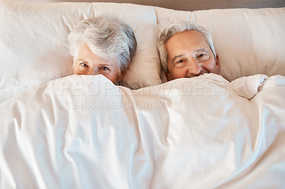 Buy stock photo Cropped shot of a playful senior couple hiding under the covers while in bed together in a nursing home