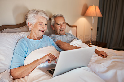 Buy stock photo Cropped shot of a happy senior woman using a laptop and sitting in bed with her husband at home