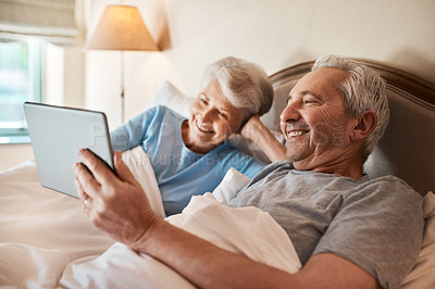 Buy stock photo Cropped shot of a happy senior couple sitting together in bed and using a tablet in a nursing home