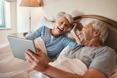Buy stock photo Cropped shot of a happy senior couple sitting together in bed and using a tablet in a nursing home