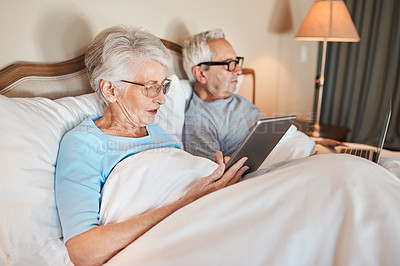 Buy stock photo Cropped shot of a senior couple sitting in bed together and using technology in a nursing home