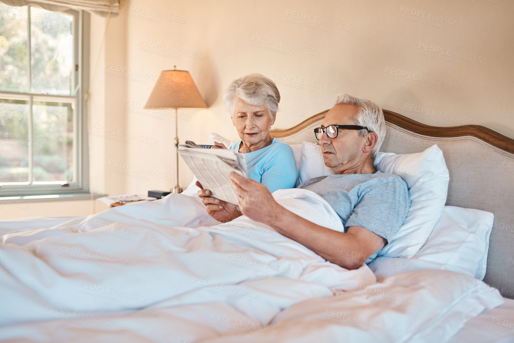 Buy stock photo Senior, couple and relax with newspaper in bedroom for daily news, article and information in morning on local community. Old man, woman and home with newsletter for headlines, media and reports.