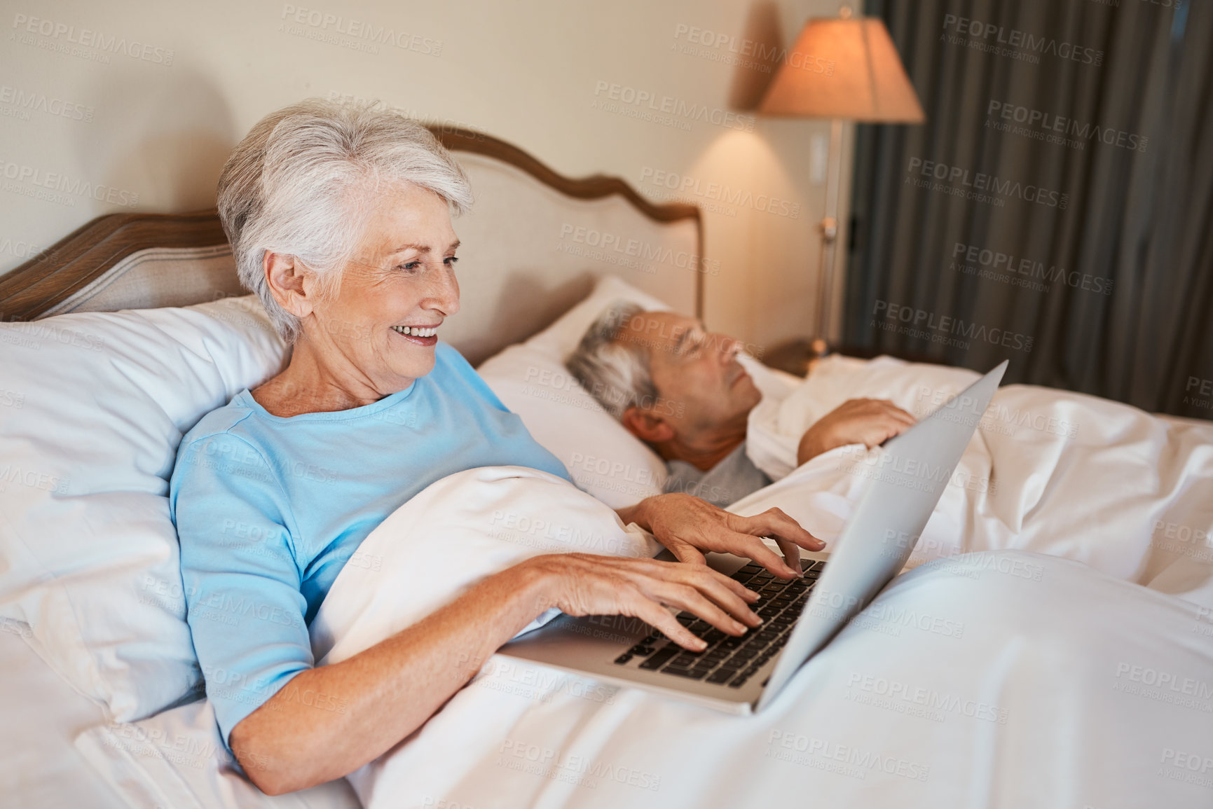 Buy stock photo Senior, happy woman and typing with laptop in bed for social media, entertainment or writing at home. Elderly, female person and computer with smile for online browsing or entertainment in bedroom