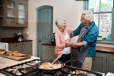Buy stock photo Cropped shot of a senior couple dancing while cooking in the kitchen at home