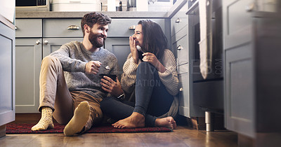 Buy stock photo Shot of a happy young couple sharing a tub of ice cream in their kitchen at home