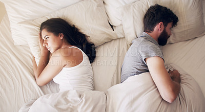 Buy stock photo Shot of a young couple ignoring each other in the bedroom at home