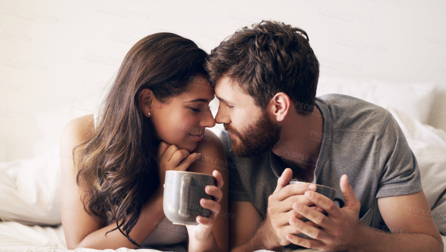 Buy stock photo Shot of a happy young couple having coffee together in bed at home