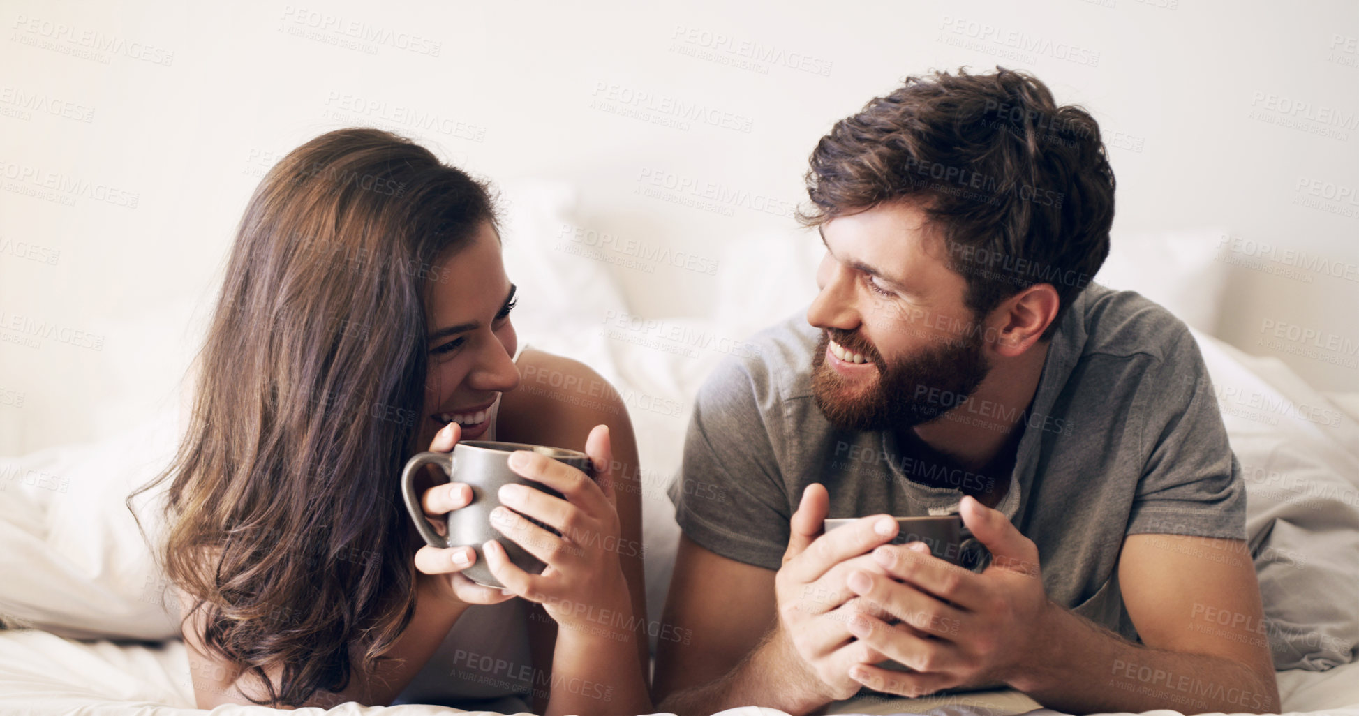 Buy stock photo Shot of a happy young couple having coffee together in bed at home