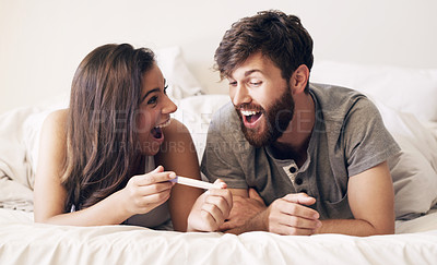 Buy stock photo Shot of a happy young couple taking a pregnancy test at home