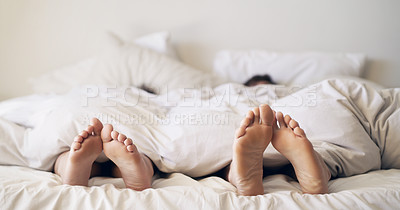 Buy stock photo Shot of a couple’s feet poking out from under the bed sheets