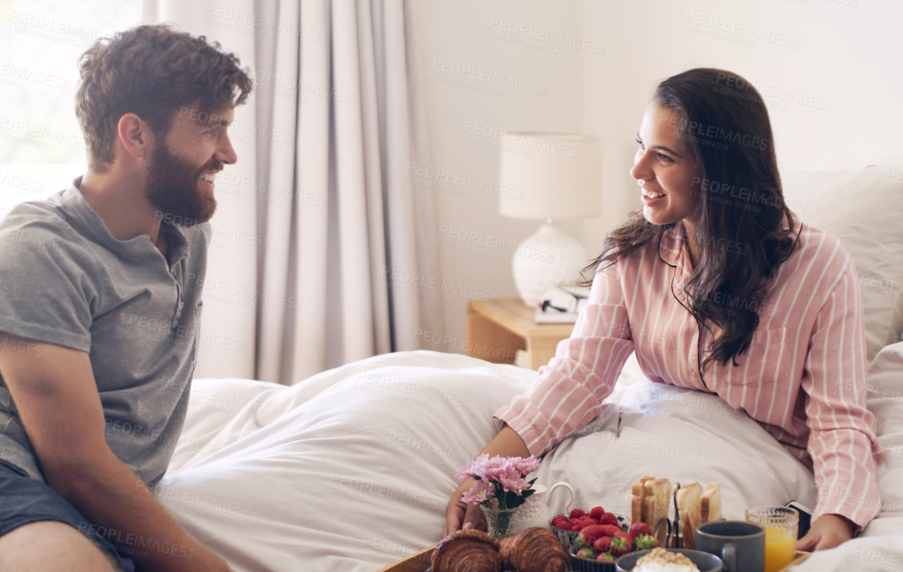 Buy stock photo Couple, love and breakfast in bed, food and morning for romance in house, man and woman with care. Apartment, date and hungry for strawberry in bedroom, anniversary and smile for celebration in home