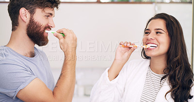 Buy stock photo Shot of a happy young couple brushing their teeth together at home