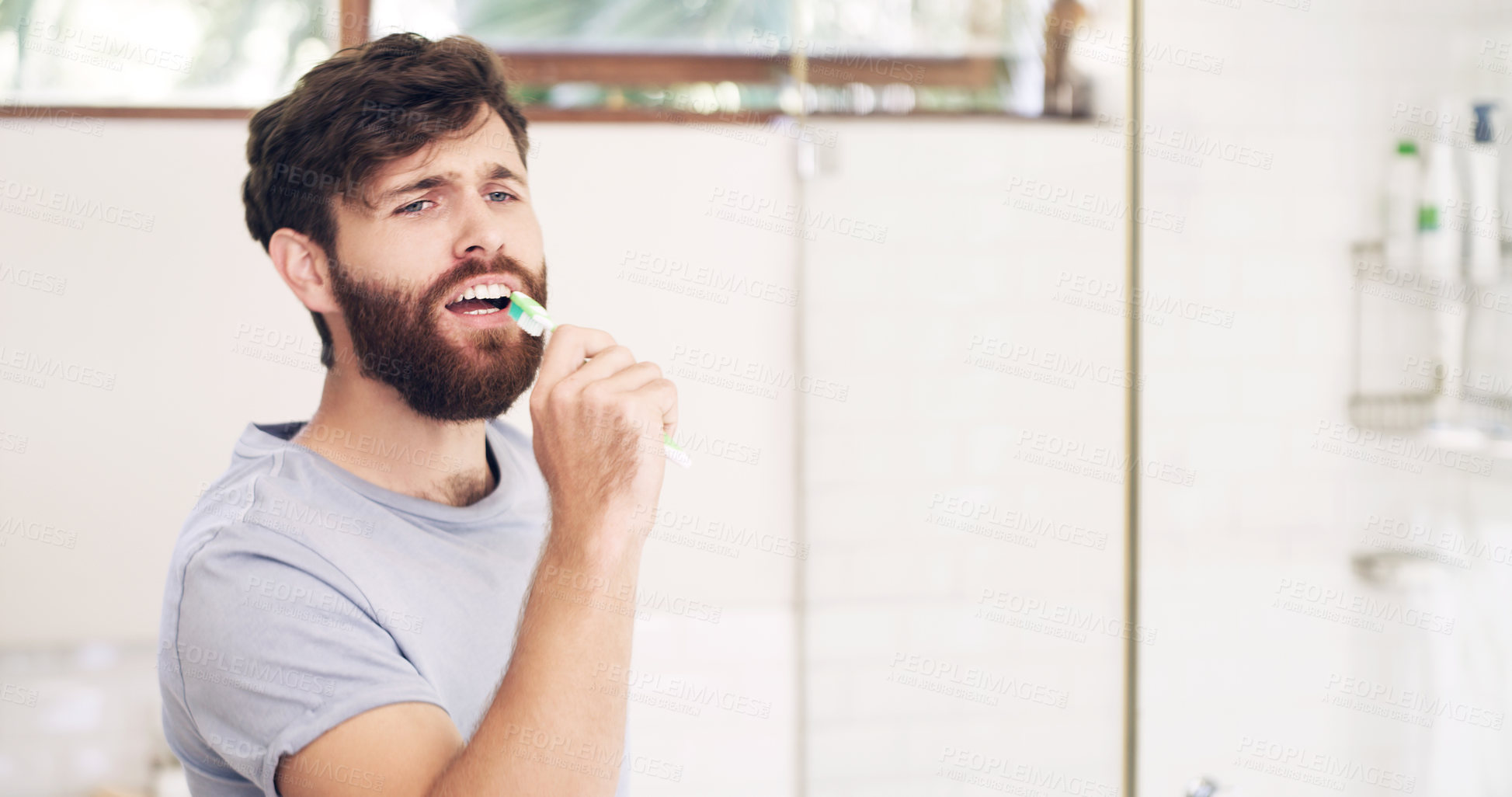 Buy stock photo Shot of a handsome young man singing while brushing his teeth at home