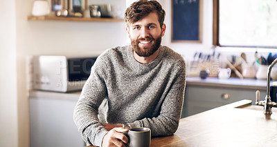 Buy stock photo Shot of a handsome young man having a cup of coffee in the kitchen at home