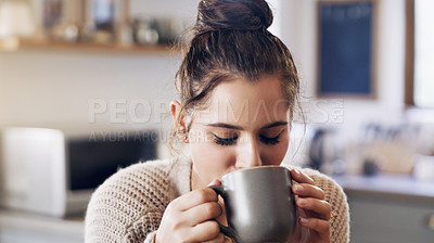 Buy stock photo Shot of a beautiful young woman having a cup of coffee in the kitchen at home