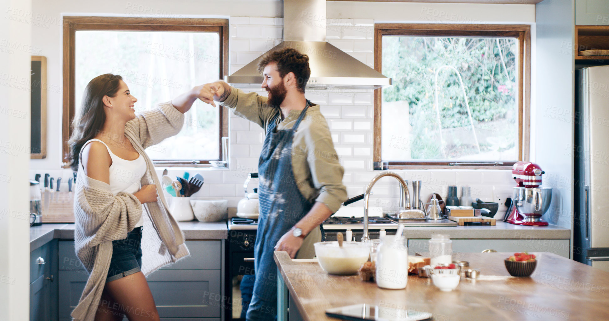 Buy stock photo Shot of a happy young couple dancing in the kitchen while preparing breakfast at home