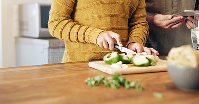 Buy stock photo Cropped shot of a couple using a digital tablet while preparing a meal at home