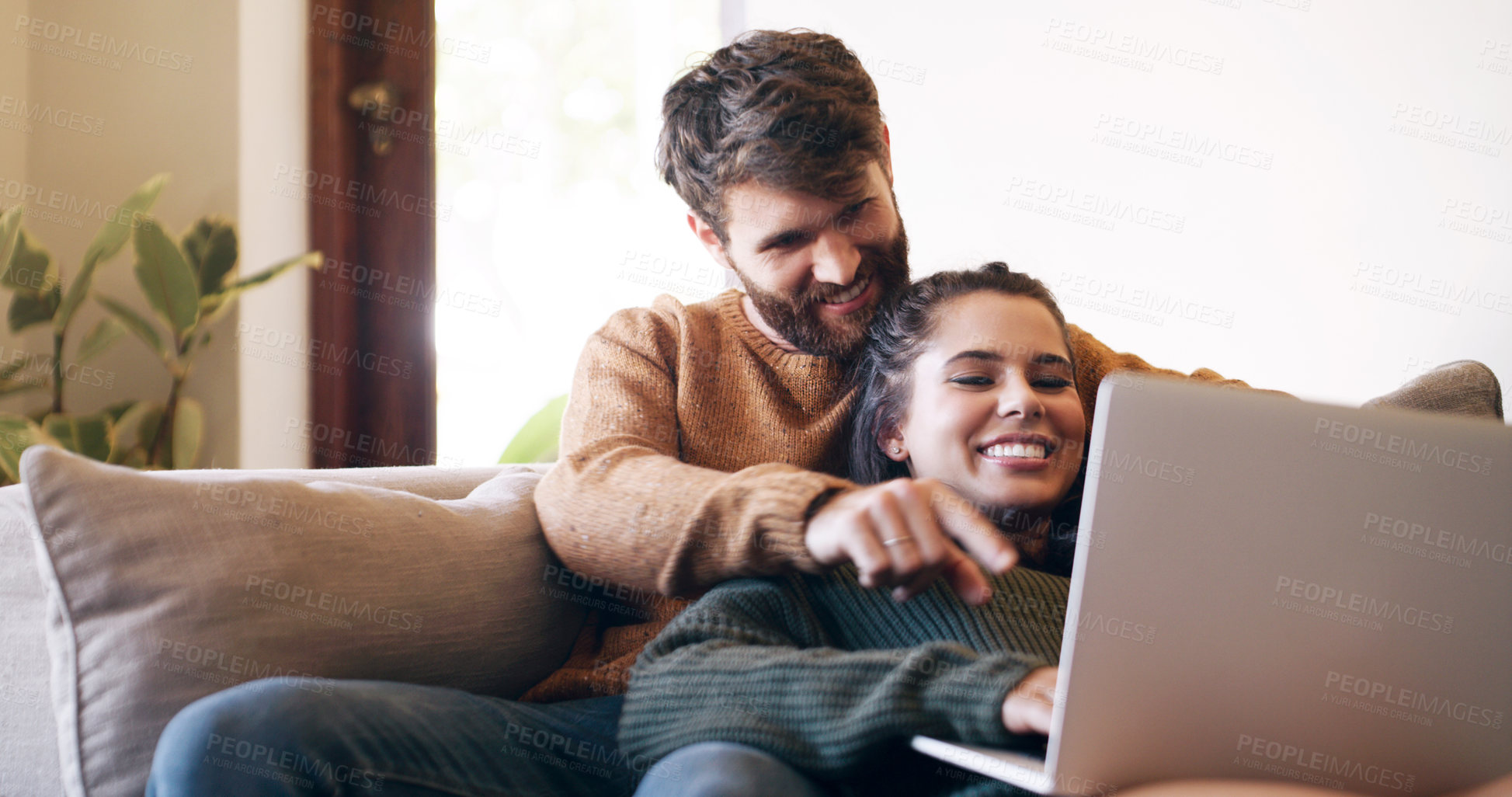 Buy stock photo Shot of a young couple using a laptop while relaxing on the sofa at home