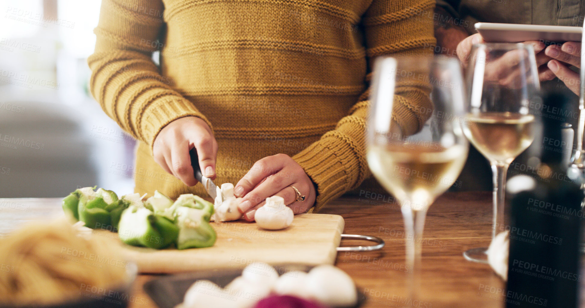 Buy stock photo Cropped shot of a couple using a digital tablet while preparing a meal at home