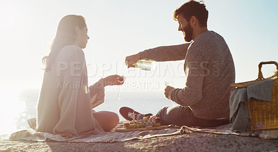 Buy stock photo Rearview shot of a young couple having a picnic on the beach