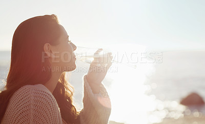 Buy stock photo Cropped shot of a young woman drinking a glass of wine on the beach