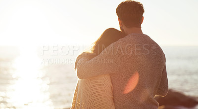 Buy stock photo Rearview shot of a young couple watching the sunset on the beach
