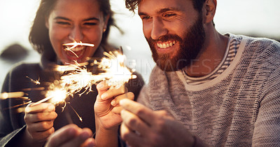 Buy stock photo Cropped shot of a young couple holding sparklers on the beach