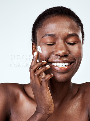 Buy stock photo Studio shot of a beautiful young woman applying moisturiser against a grey background