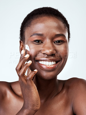 Buy stock photo Studio portrait of a beautiful young woman applying moisturiser against a grey background