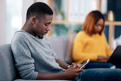 Buy stock photo Relax, phone or technology addiction and a black man on the living room sofa of his home with his girlfriend on a blurred background. Mobile, contact and social media with a male person in a house