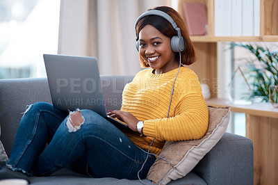 Buy stock photo Shot of an attractive young woman wearing headphones while using her laptop