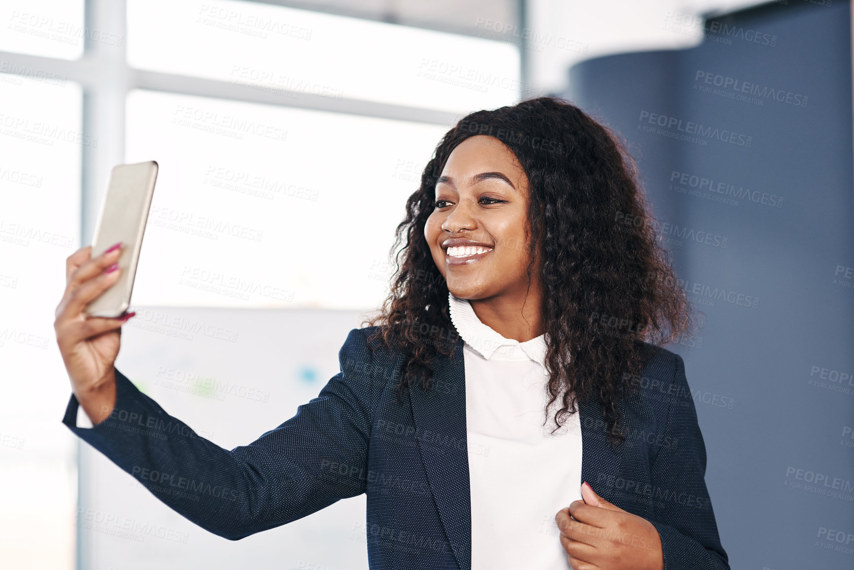 Buy stock photo Shot of a young businesswoman taking a selfie with a smartphone in a modern office