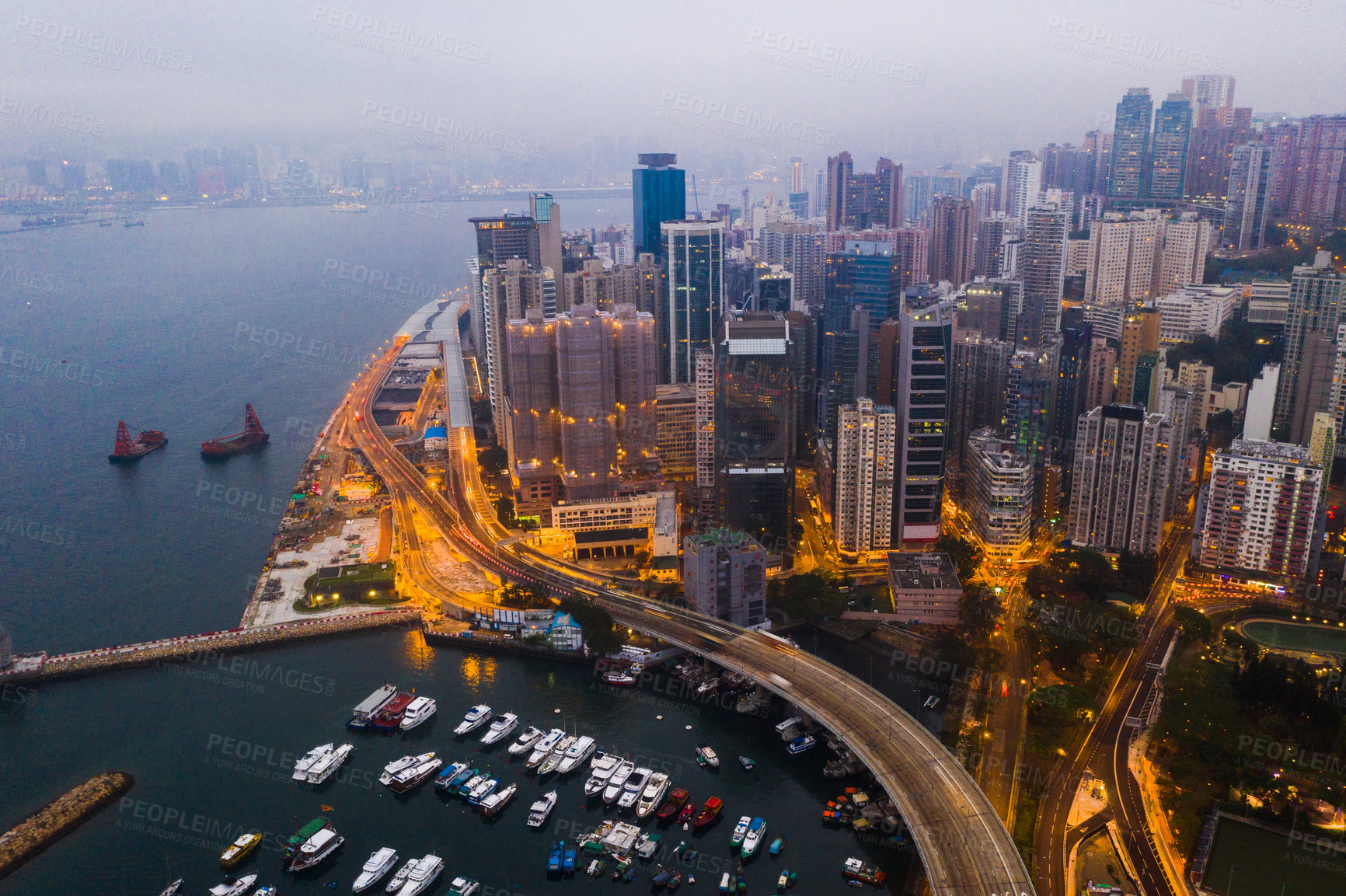 Buy stock photo Buildings, ocean and aerial view of the city at night with lights, boats and ships on the sea harbor. Landscape, architecture and drone of an urban town with skyscrapers, yachts and infrastructure.