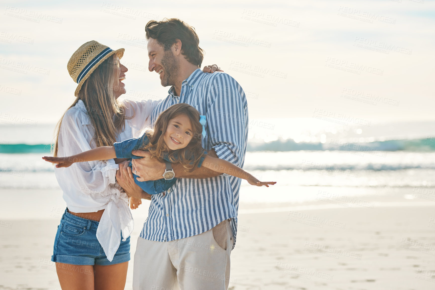 Buy stock photo Cropped shot of an affectionate couple playing with their daughter during an enjoyable day out on the beach