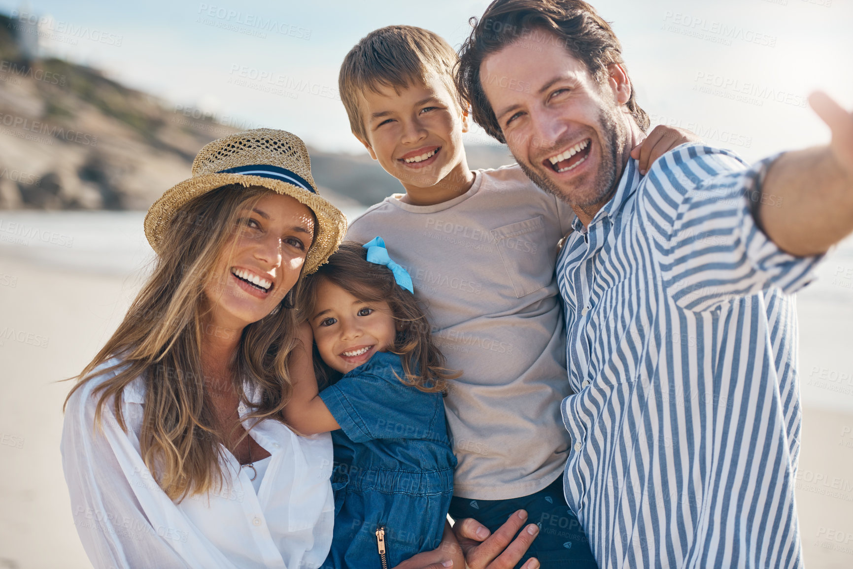 Buy stock photo Cropped portrait of an affectionate couple carrying their two children and posing for a selfie on the beach