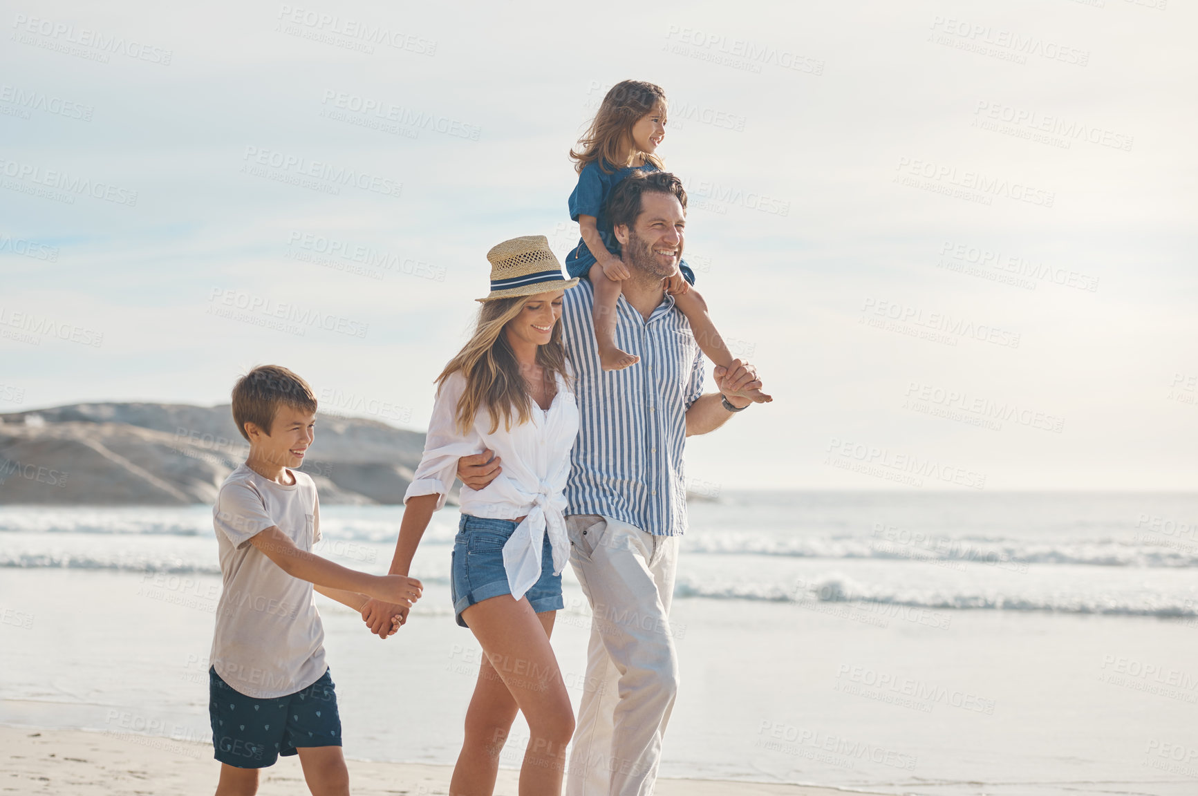 Buy stock photo Cropped shot of an affectionate couple holding hands with their two young children and walking along the beach