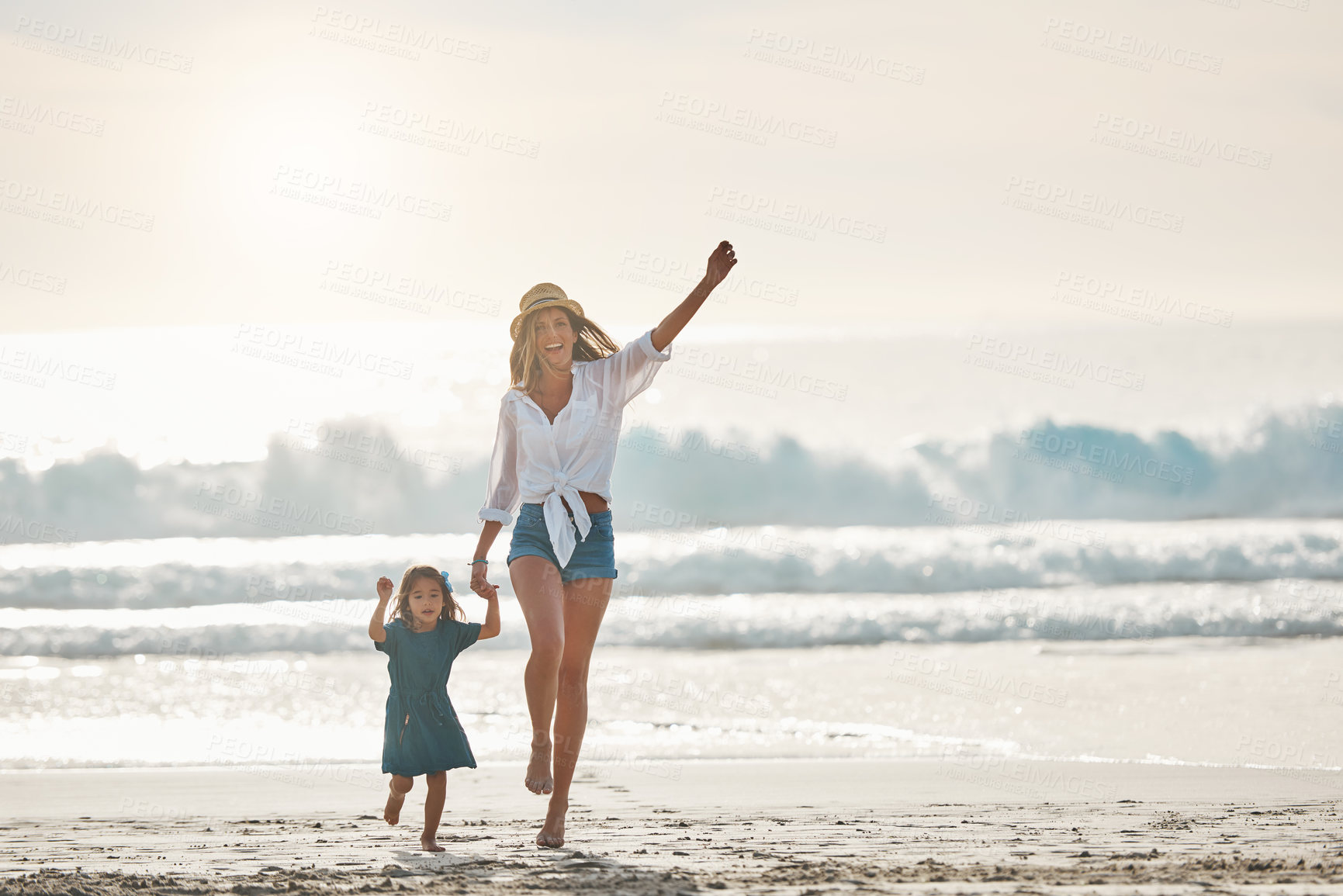 Buy stock photo Full length portrait of an affectionate young mother holding her daughter's hand and walking on the beach