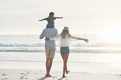 Buy stock photo Rearview shot of an unrecognizable father carrying his daughter on his shoulders and walking on the beach with his wife