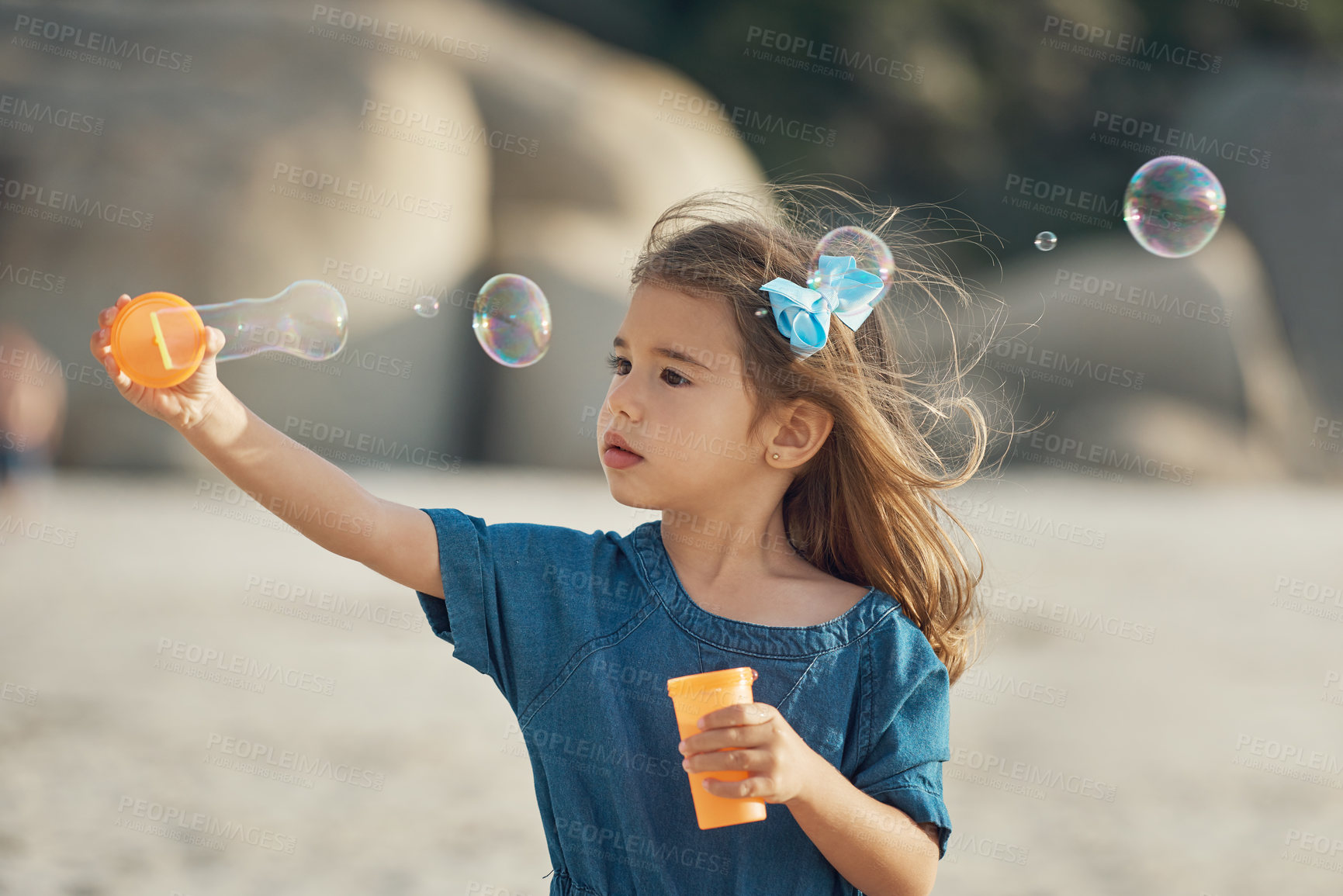 Buy stock photo Cropped shot of a young girl standing alone and blowing bubbles during an enjoyable day on the beach
